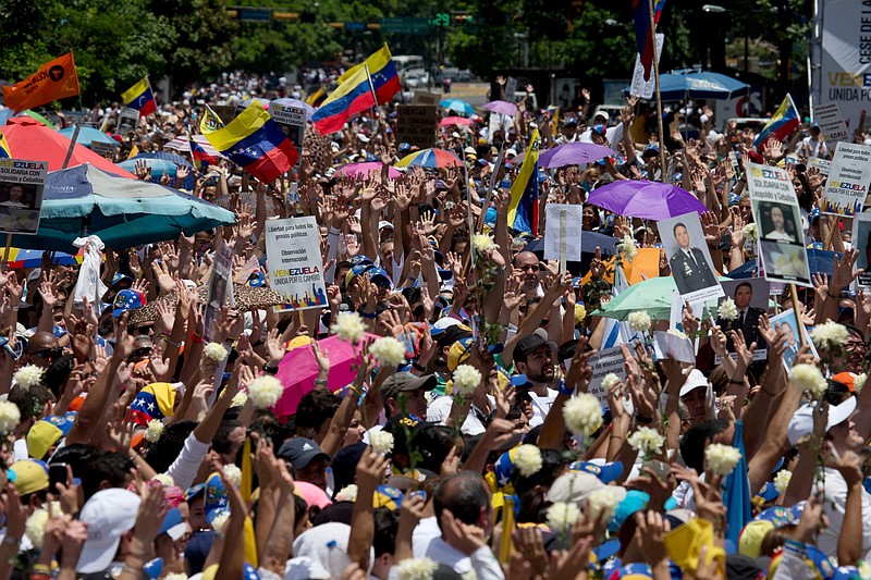 
              Opposition demonstrators hold up white flowers and pictures of political prisoners as they protest the government in Caracas, Venezuela, Saturday, May 30, 2015. Venezuelans gathered across the country to voice their anger with the administration and demand a firm date for this year's legislative elections. (AP Photo/Fernando Llano)
            