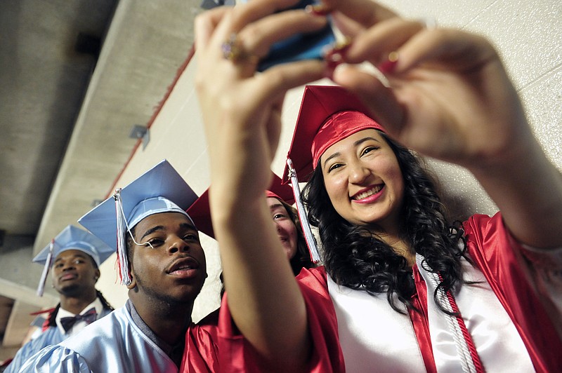 
              ADVANCE FOR WEEKEND EDITIONS MAY 30-31 - In this May 17, 2015 photo, Geraldine Hernandez, right, takes a picture with friends Leonard Williams, left, and Micaela Herrera as they prepare to graduate from Glencliff High School in Nashville, Tenn. Tennessee Promise is bringing changes to every corner of the state. Volunteer State Community College in Sumner County is hiring four "completion advisers," a new role that will help more students leave campus with a degree in two years. (Samuel M. Simpkins/The Tennessean via AP) NO SALES
            