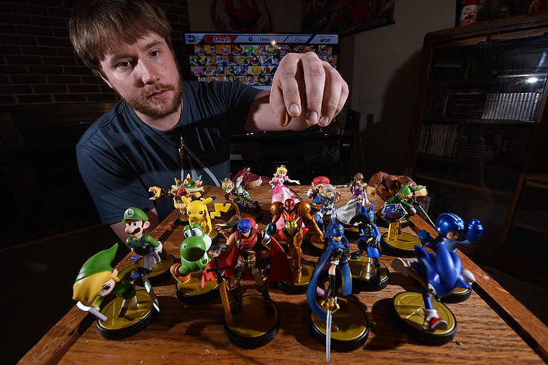 Ringgold, Ga., resident Andrew Morgan reaches for one of more than 20 Nintendo Amiibo figures he's collected. The toysto- life figurines feature embedded technology that allow them to unlock hidden content in video games by being synchronized to compatible titles on the Nintendo Wii U console and 3DS handheld.