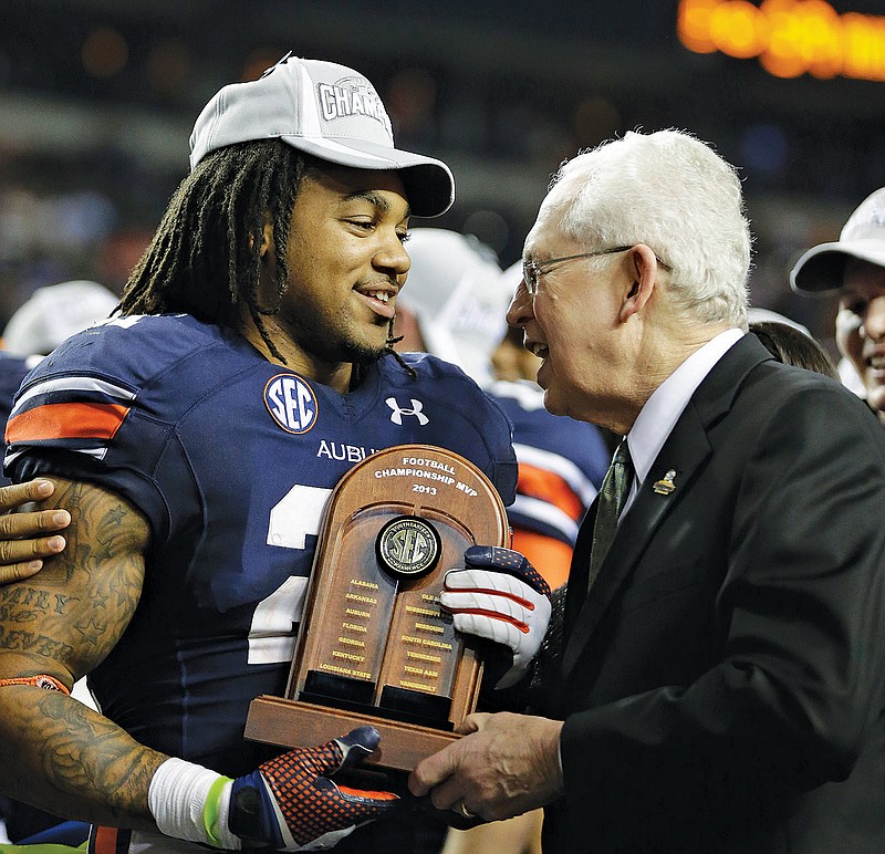 Southeastern Conference commissioner Mike Slive, right, presents the MVP trophy to Auburn's Tre Mason after the 2013 SEC football championship game against Missouri. Slive steps aside today.