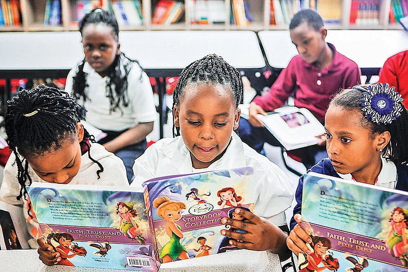 In this Tuesday, April 15, 2014, photo, Brianna Reed, 7, center, reads out loud to the rest of the participating students at Knowledge Quest, one of dozens of nonprofit groups with an after-school tutoring program in Memphis, Tenn. The Shelby County Schools system is going to hire a lawyer so the district can begin the "appropriate legal action" to force the state to properly fund schools through the Basic Education Program.