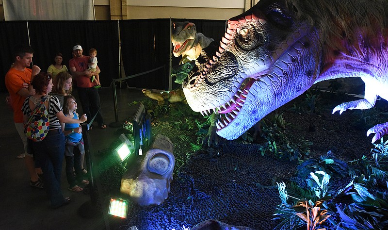 A pair of animated Tyrannosaurus Rex dinosaurs menace visitors to the traveling exhibit, "Discover the Dinosaurs" at the Chattanooga Convention Center on Sunday, May 31, 2015, in Chattanooga.