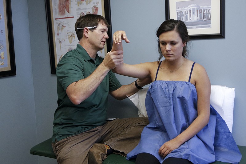 Orthopedic Dr. Jad Dorizas, left, checks the shoulder of patient Betsy Ware on Wednesday, June 3, 2015, in the offices of UT Erlanger OrthoSouth at Erlanger Hospital in Chattanooga, Tenn. TennCare will be changing the way it reimburses doctors, including orthopedic surgeons.