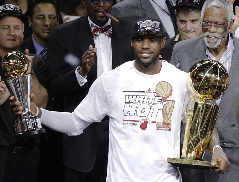 
              FILE - In this June 21, 2013, file photo, Miami Heat's LeBron James holds the Bill Russell NBA Finals Most Valuable Player Award in his left hand and the Larry O'Brien NBA Championship Trophy after Game 7 of the NBA basketball finals in Miami. The Heat defeated the San Antonio Spurs to win their second straight NBA championship. Bill Russell is at right rear. Miami changed James for the better. He came back to Ohio more confident, more determined--a two-time NBA champion. He's now drawing on his experiences to make a run at another title. (AP Photo/Wilfredo Lee, File)
            