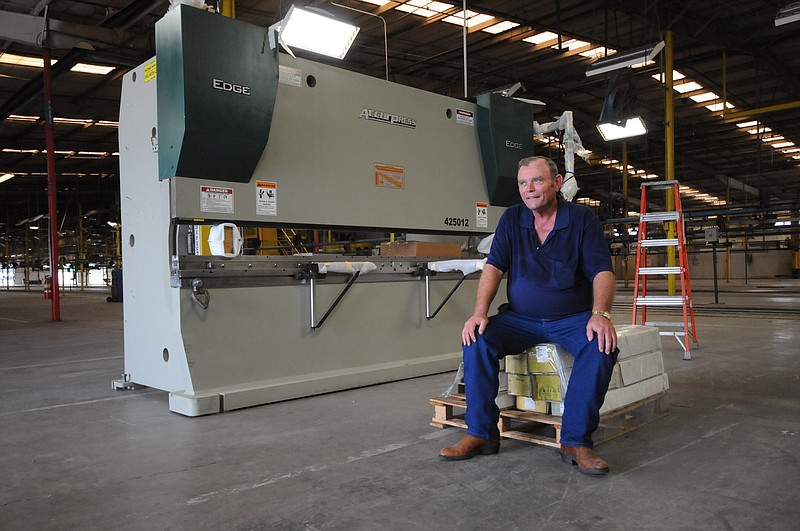 Randy Phillips, owner and president of Phillips Bros. Machine Co. sits next to a a 14-ton press designed to shape steel in this 2012 file photo