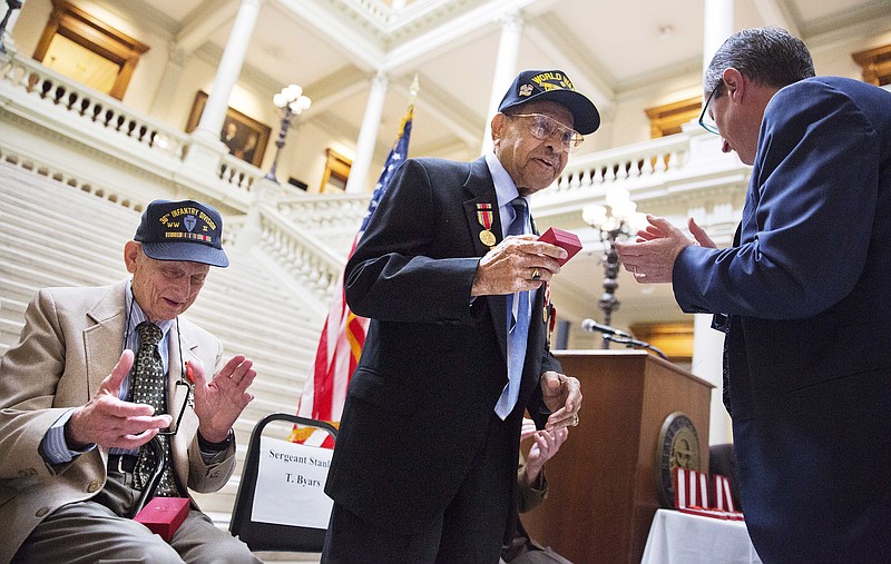 
              World War II veteran Stanley Byars, 92, of Atlanta, center, receives the French Legion of Honor medal from Denis Barbet, the consul general of France in Atlanta, right, as fellow veteran Neill Jack Cox, 90, of Clermont, Ga., left, applauds during a ceremony at the Capitol Thursday, June 4, 2015, in Atlanta. The Legion of Honor is the highest distinction France can award to a citizen or foreigner. The Ten WWII veterans who were honored Thursday fought on French territory as part of the liberation of the country from Nazi Germany and were nominated by President Francois Hollande. Regularly under enemy fire, Byars was the sole survivor of machine gun fire from a single German fighter plan that attacked his five-truck convoy. (AP Photo/David Goldman)
            