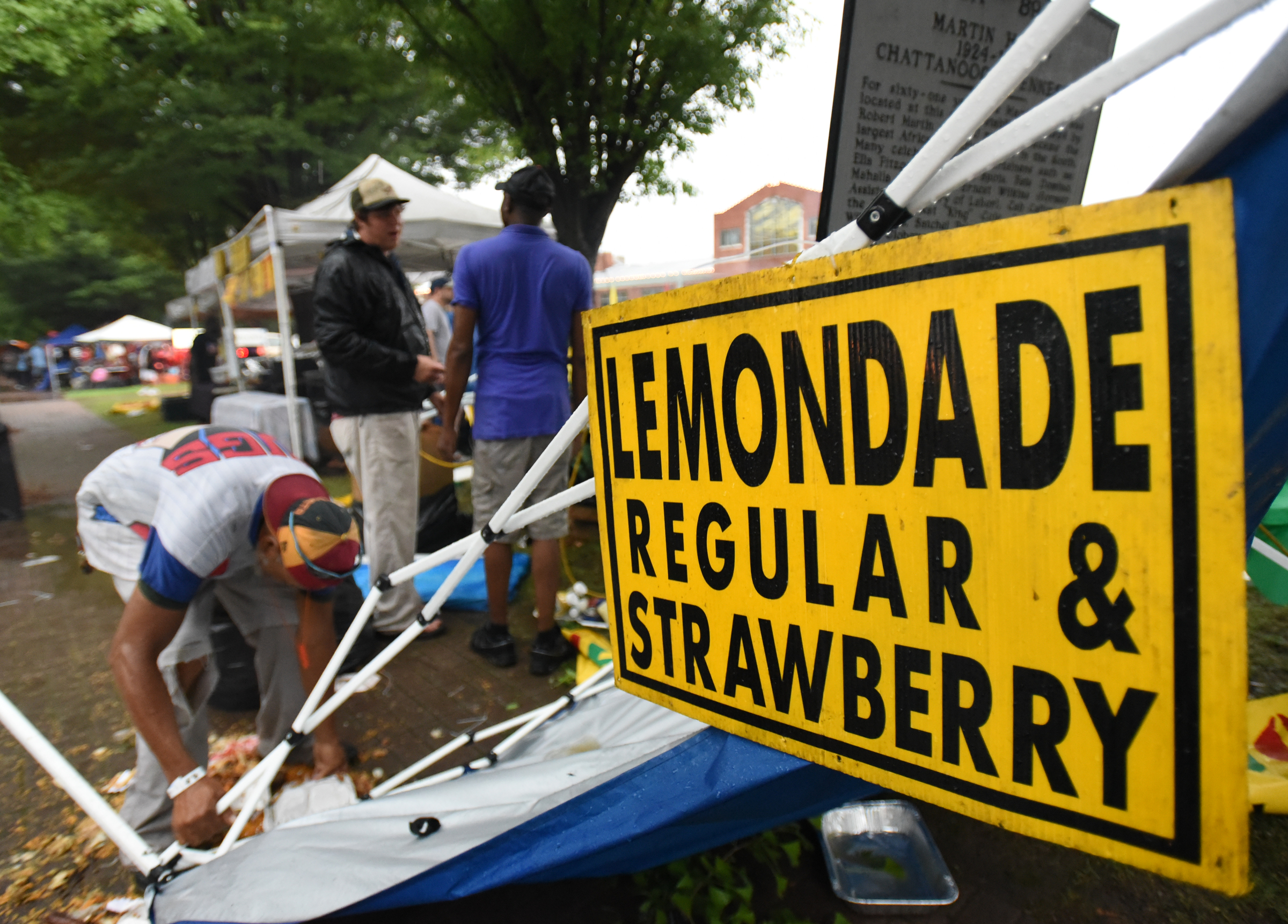 Staff Photo by Angela Lewis Foster/ The Chattanooga Times Free Press- 6/08/15
People work to clean up the mess after the tent of a vendor who was selling Jamaican food collapsed in the rain storm Monday at the Bessie Smith Strut.