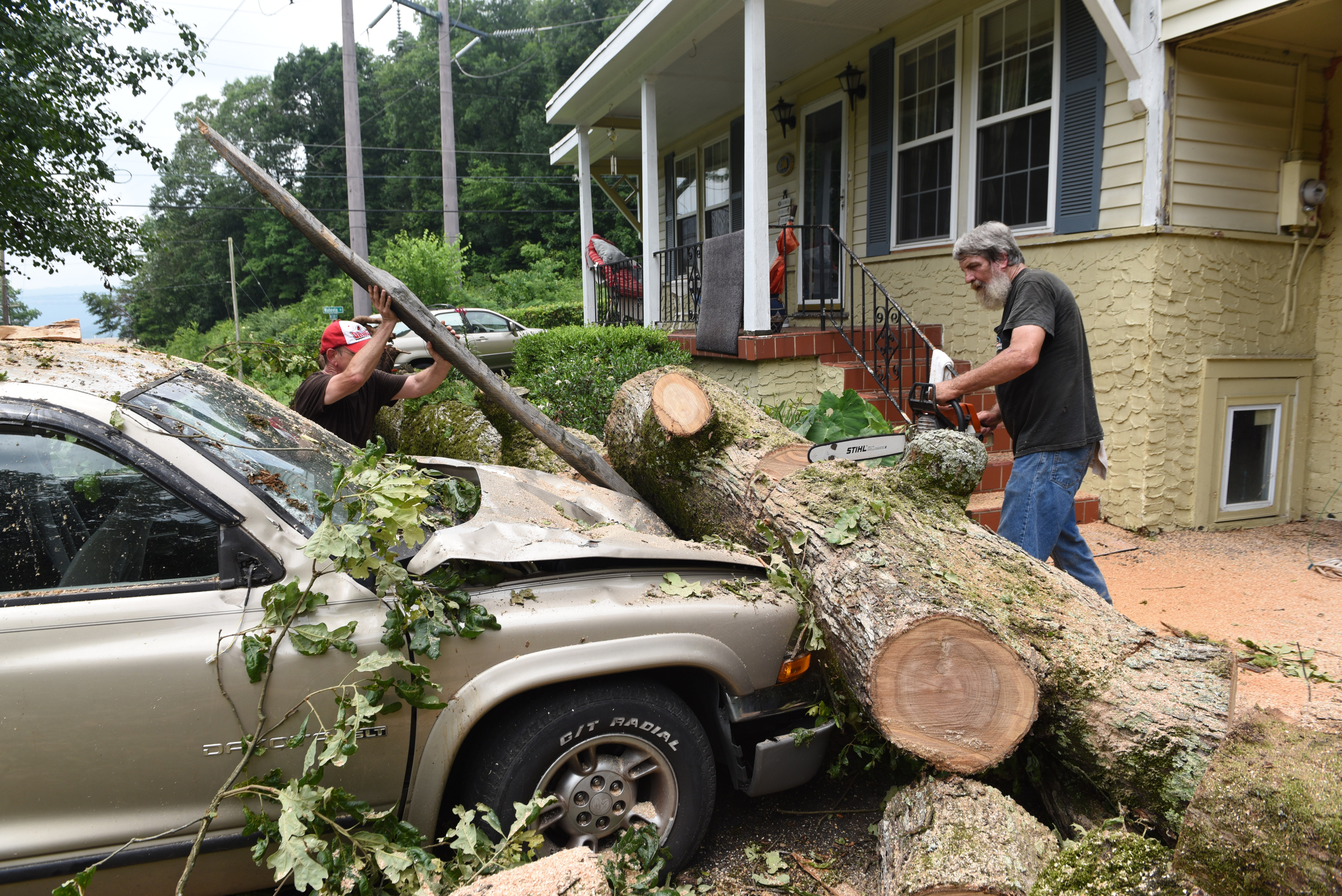 Staff photo by John Rawlston/Chattanooga Times Free Press - {iptcmonthname3 {iptcday}, 2015
Ronnie Morgan, left, uses a broken board from his carport to remove a large oak tree trunk from the hood of his truck after neighbor Ron Hoyle used a chain saw to cut the tree as they cleans up damage from Monday night storms on Tuesday, June 9, 2015, in Rossville, Ga.