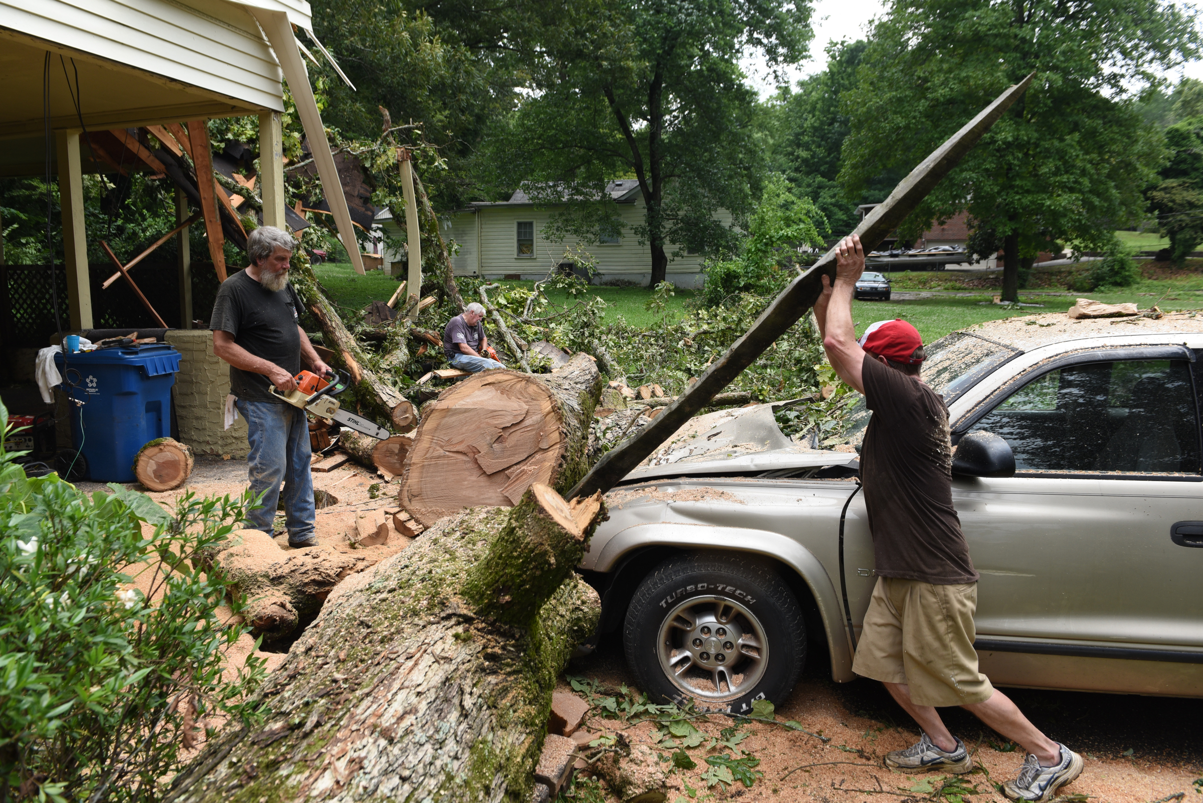 Staff photo by John Rawlston/Chattanooga Times Free Press - {iptcmonthname3 {iptcday}, 2015
Ronnie Morgan, right, uses a broken board from his carport to remove a large oak tree trunk from the hood of his truck after neighbor Ron Hoyle used a chain saw to cut the tree as they cleans up damage from Monday night storms on Tuesday, June 9, 2015, in Rossville, Ga.