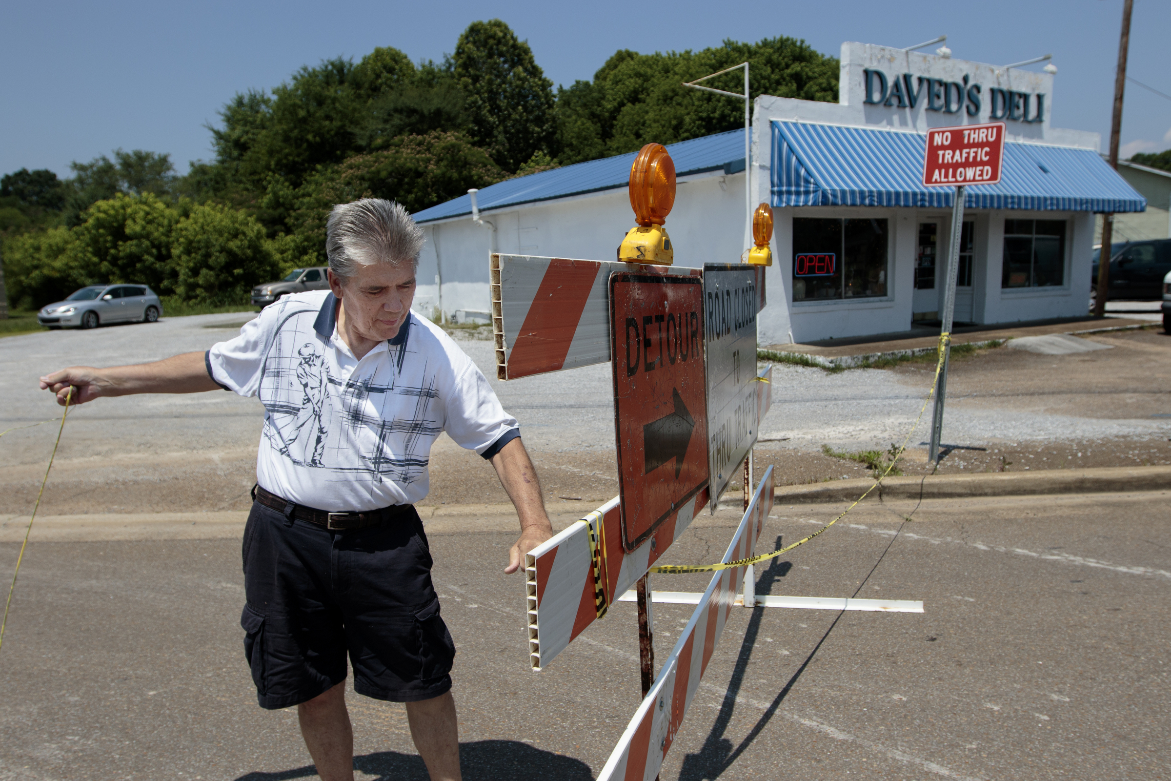 Staff photo by Doug Strickland
Daved Senters, owner of Daved's Deli, tears away caution tape from a road closure sign which is blocking off a portion of the gravel lot of his deli located at the intersection of Middle Valley Road and Thrasher Pike where Middle Valley Road has been temporarily closed for the construction of a new Wal Mart Neighborhood Market store Wednesday, June 10, 2015, in Hixson, Tenn.
