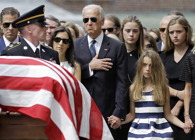 In this June 6, 2015 file photo, Vice President Joe Biden, accompanied by his family, holds his hand over his heart as he watches an honor guard carry a casket containing the remains of his son.