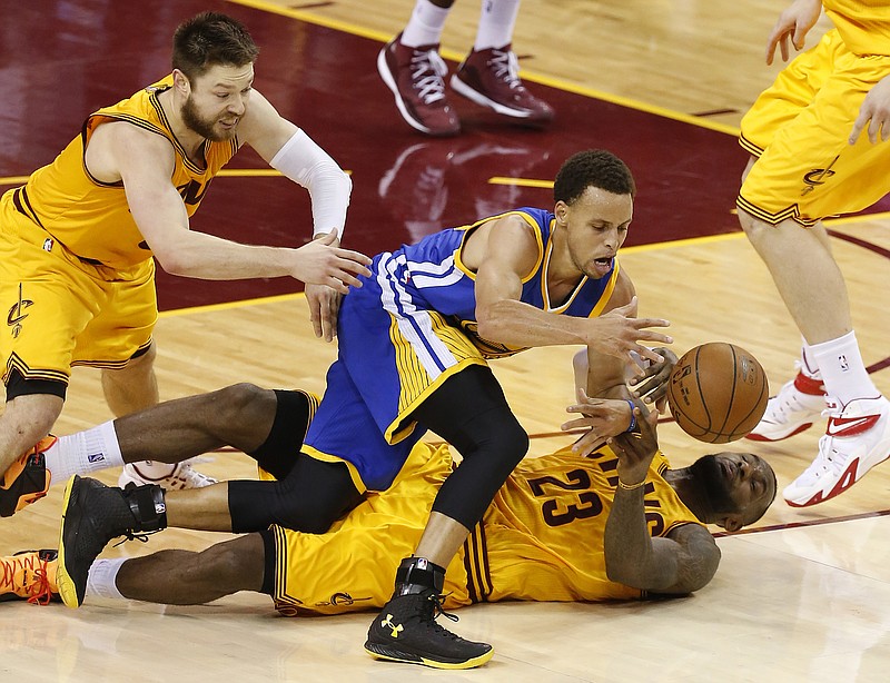 
              Golden State Warriors guard Stephen Curry and Cleveland Cavaliers forward LeBron James (23) and guard Matthew Dellavedova, left, go to the floor for a loose ball during the second half of Game 3 of basketball's NBA Finals in Cleveland, Tuesday, June 9, 2015. (AP Photo/Paul Sancya)
            