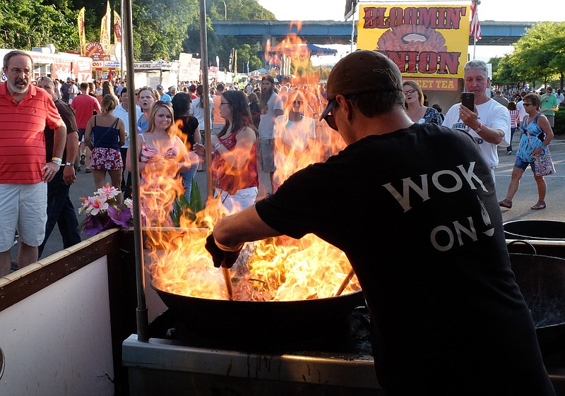 Wearing his "Wok On" tee-shirt, Joel Johnston fires up his vegetables as a crowd gathers to watch at the Island Noodles concession Friday evening at Riverbend. "It's all vegan until you tell us you want chicken in it," Johnston said.