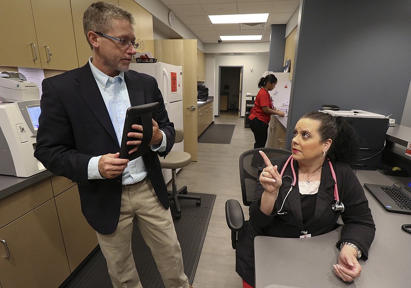 Staff Photo by Dan Henry / The Chattanooga Times Free Press- 6/12/15. Dr. Glenn Harnett, Chief Medical Officer for the new American Family Care in Fort Oglethorpe, Ga., speaks to medical assistant Sharon Owens while at their new facility which opened in May of 2015. 