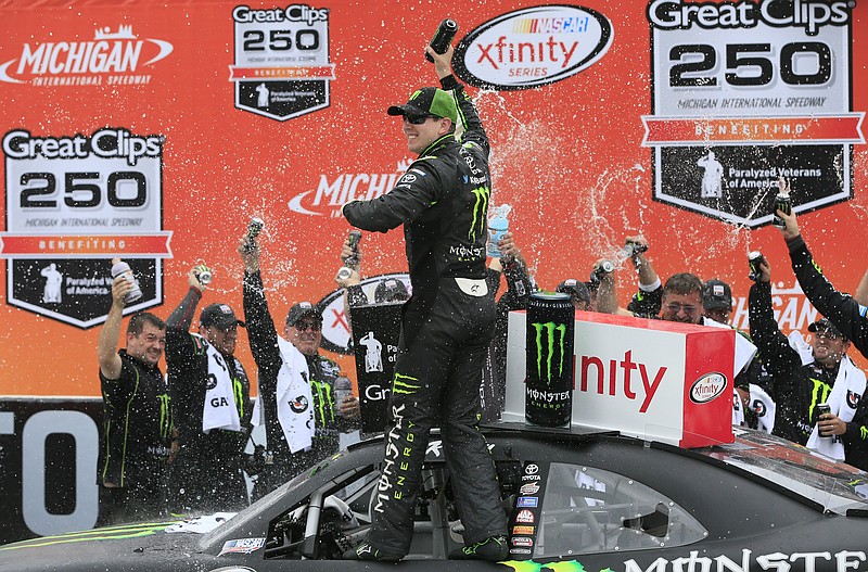 Kyle Busch celebrates in the winner's circle after winning the NASCAR Xfinity series auto race at Michigan International Speedway, Saturday, June 13, 2015, in Brooklyn, Mich.