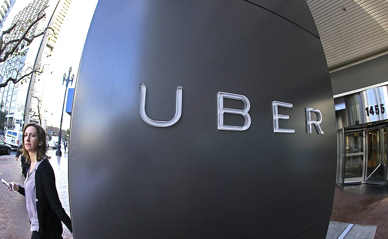 In this Tuesday, Dec. 16, 2014, photo, a woman leaves the headquarters of Uber in San Francisco.