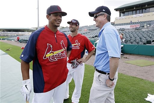 In this Feb. 25, 2013, file photo, Houston Astros general manager Jeff Luhnow, right, talks to St. Louis Cardinals center fielder Jon Jay, left, and second baseman Daniel Descalso before an exhibition spring training baseball game in Jupiter, Fla. Major League Baseball says it is cooperating with a federal investigation into an illegal breach of the Astros' internal operations database, amid a report that the Cardinals were responsible for the hack. The New York Times, citing unnamed law enforcement officials, reported Tuesday, June 16, 2015 , that the FBI and Justice Department are investigating whether Cardinals' front-office officials are responsible for the effort to steal information about player personnel. The The teams were rivals in the National League Central until Houston moved to the American League in 2012. (AP Photo/Julio Cortez, File)