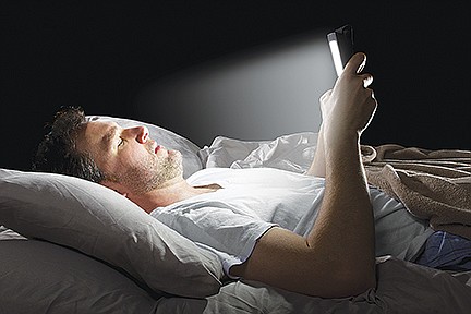 Male in bed browsing the internet late with a tablet