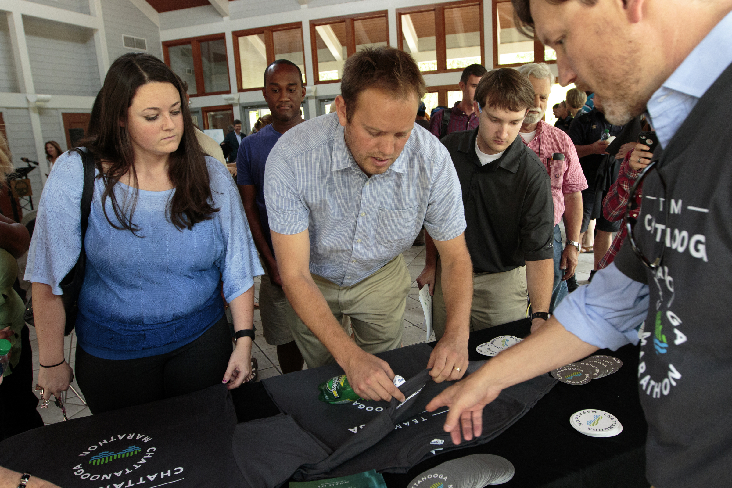 Staff photo by Doug Strickland
People pick up Chattanooga Marathon t-shirts and stickers after its announcement at a news conference Thursday, June 18, 2015, at Coolidge Park in Chattanooga, Tenn. The marathon is set to take place March 4-6 of 2016.