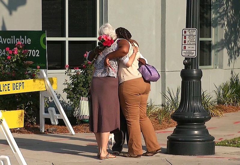 In this image taken from video on Thursday, June 18, 2015, Martha Watson, left, and Tarsha Moseley embrace at a makeshift memorial near Emanuel AME Church in Charleston, S.C. A white man opened fire during a prayer meeting inside the historic black church Wednesday night, killing several people. The shooter remained at large Thursday morning.