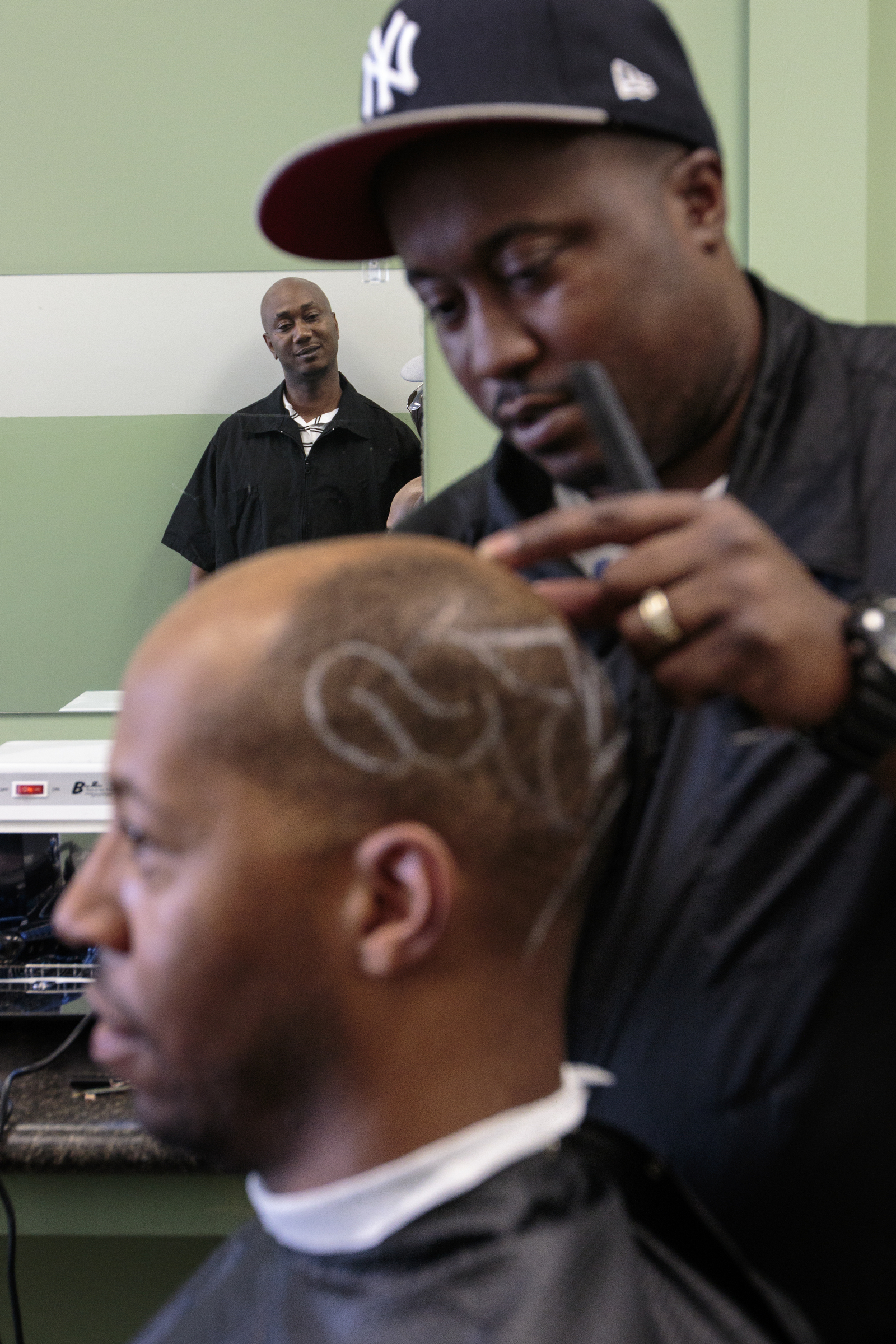 Staff photo by Doug Strickland
Tim Baker, reflected in a mirror, watches as Thomas Evans, right, cuts Jumaane Lanier's hair Wednesday, June 17, 2015, at Baker's Barber College in Chattanooga, Tenn. Evans has been training at the school since Baker opened the barber college at the beginning of May.