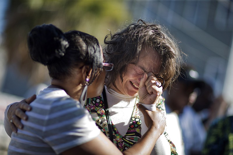 Angela Hines, left, comforts Auburn Sandstrom as she cries while visiting a sidewalk memorial in memory of the shooting victims in front of the Emanuel A.M.E. Church in Charleston, S.C. on Saturday, June 20, 2015. (AP Photo/David Goldman)