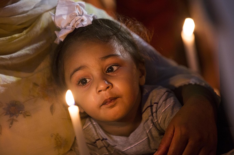 
              FILE - In this Tuesday, Aug. 7, 2012 file photo, a child looks at a candle during a vigil at the Oak Creek Civic Center in Oak Creek, Wis. for the victims of a mass shooting at the Sikh Temple of Wisconsin on Sunday. (AP Photo/Tom Lynn)
            