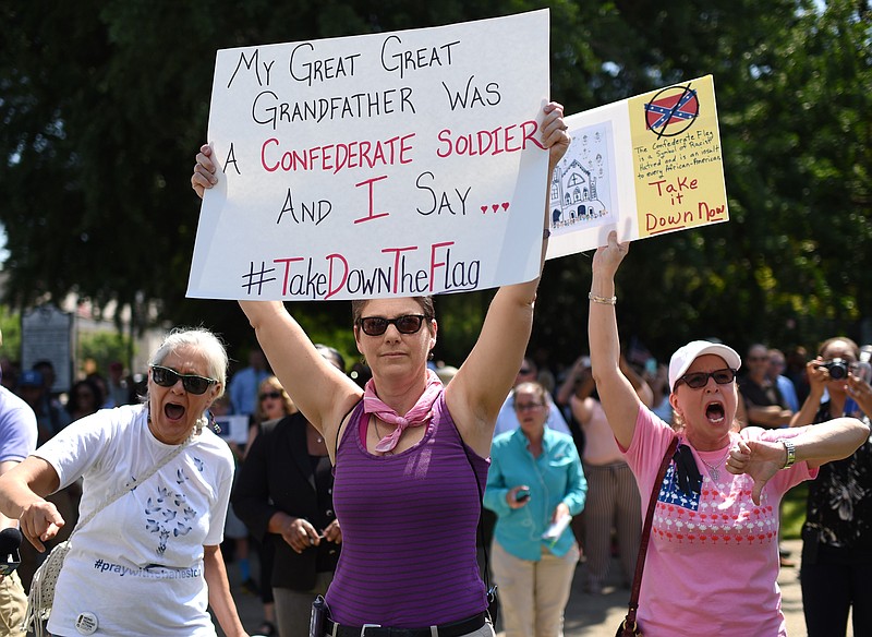 Protesters hold signs and chant Tuesday during a rally to take down the Confederate flag at the South Carolina Statehouse.