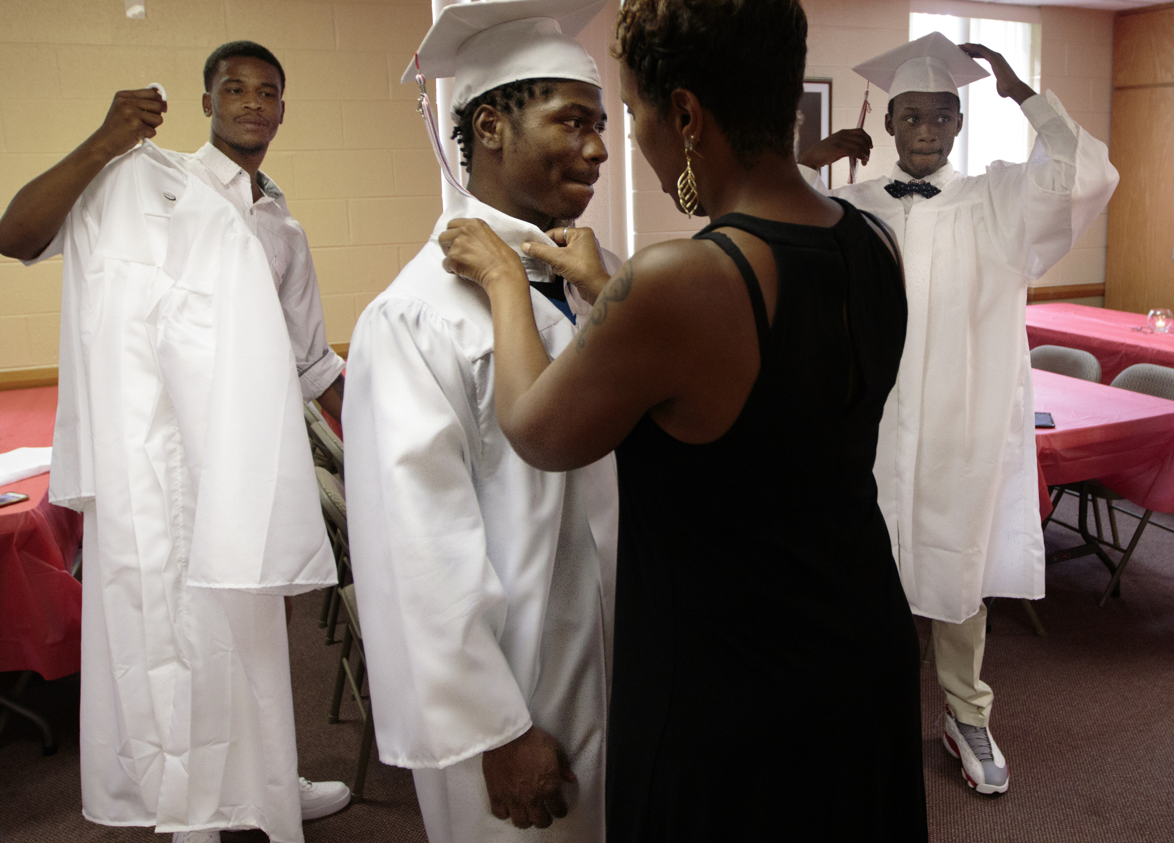 Staff photo by Doug Strickland
Markious Sims, left, and DePriest Deloney, right, put on their graduation attire as Dr. Selina Thedford, center, helps Kobeai Ford with his collar before Brainerd High School's first-ever summer graduation Tuesday, June 23, 2015, at the North Moore Road Salvation Army, across from the high school, in Chattanooga, Tenn.