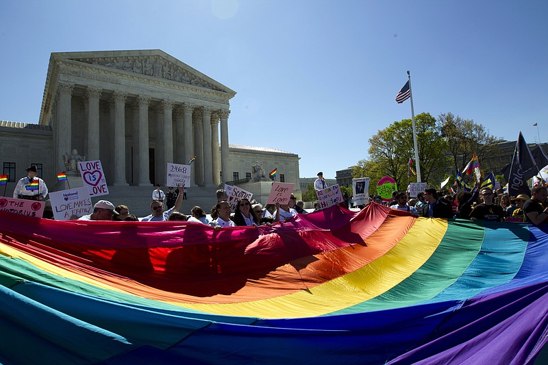 
              FILE - In this April 28, 2015, file photo, demonstrators stand in front of a rainbow flag of the Supreme Court in Washington, as the court was set to hear historic arguments in cases that could make same-sex marriage the law of the land. Gay and lesbian couples could face legal chaos if the Supreme Court rules against same-sex marriage in the next few weeks. Same-sex weddings could come to a halt in many states, depending on a confusing mix of lower-court decisions and the sometimes-contradictory views of state and local officials. Among the 36 states in which same-sex couples can now marry are 20 in which federal judges invoked the Constitution to strike down marriage bans. (AP Photo/Jose Luis Magana, File)
            