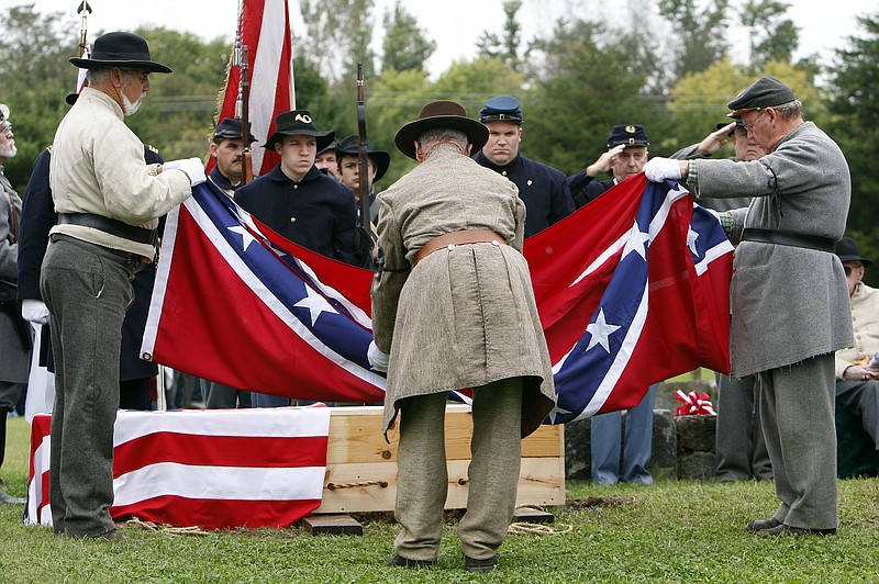 The Confederate flag is folded after it was removed from the casket containing the remains of an unknown Civil War soldier during burial in Franklin, Tenn., Saturday, Oct. 10, 2009. The body was accidentally unearthed from a shallow grave by construction workers. A Union flag is still seen covering the casket. (AP Photo/Mark Humphrey)
