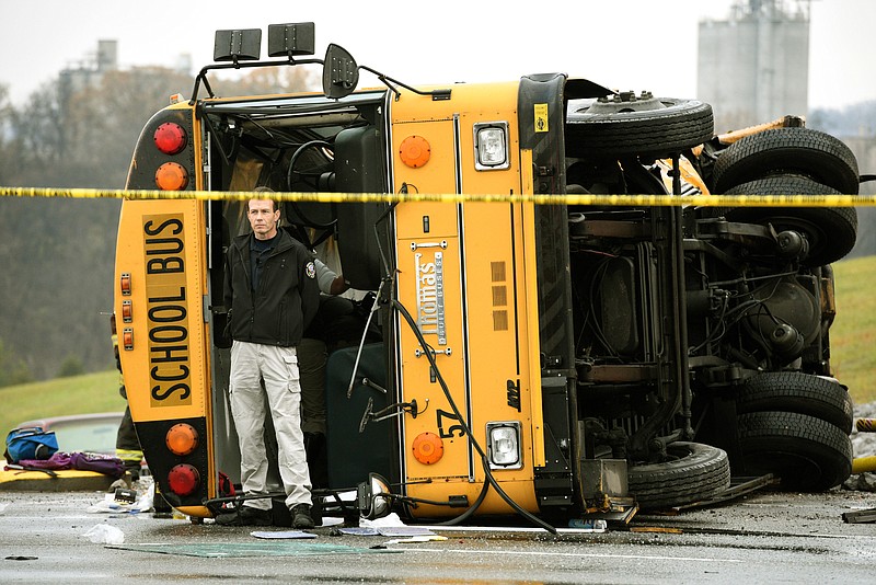 In this photo taken on Tuesday, Dec. 2, 2014, a law enforcement officer guards one of two school buses involved in a triple-fatal collision in Knoxville.