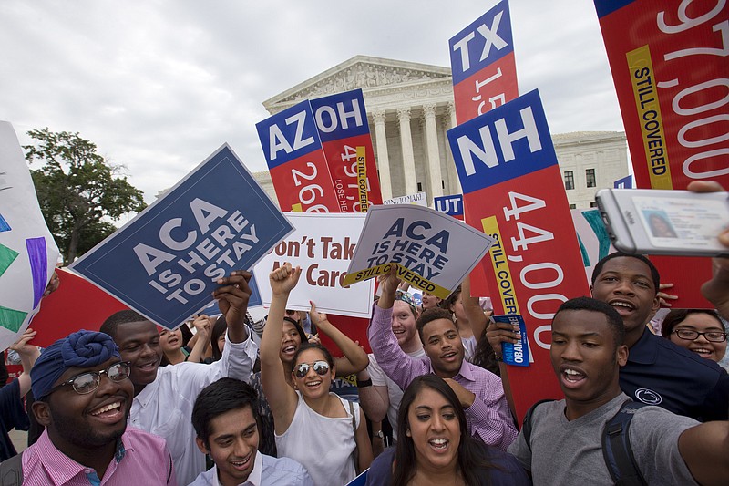 Students cheer as they hold up signs stating that numbers of people in different states who would lose healthcare coverage, with the words "lose healthcare" now over written with "still covered" stickers, after the Supreme Court decided that the without the Affordable Care Act (ACA) may provide nationwide tax subsidies, Thursday June 25, 2015, outside of the Supreme Court in Washington. (AP Photo/Jacquelyn Martin)