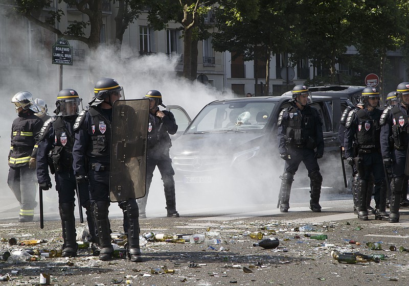 Police officers stand next to a a burned out car during a taxi drivers demonstration in Paris, France, Thursday, June 25, 2015. French taxis are on strike around the country, snarling traffic in major cities and slowing access to Paris' Charles de Gaulle airport after weeks of rising and sometimes violent tensions over Uber.