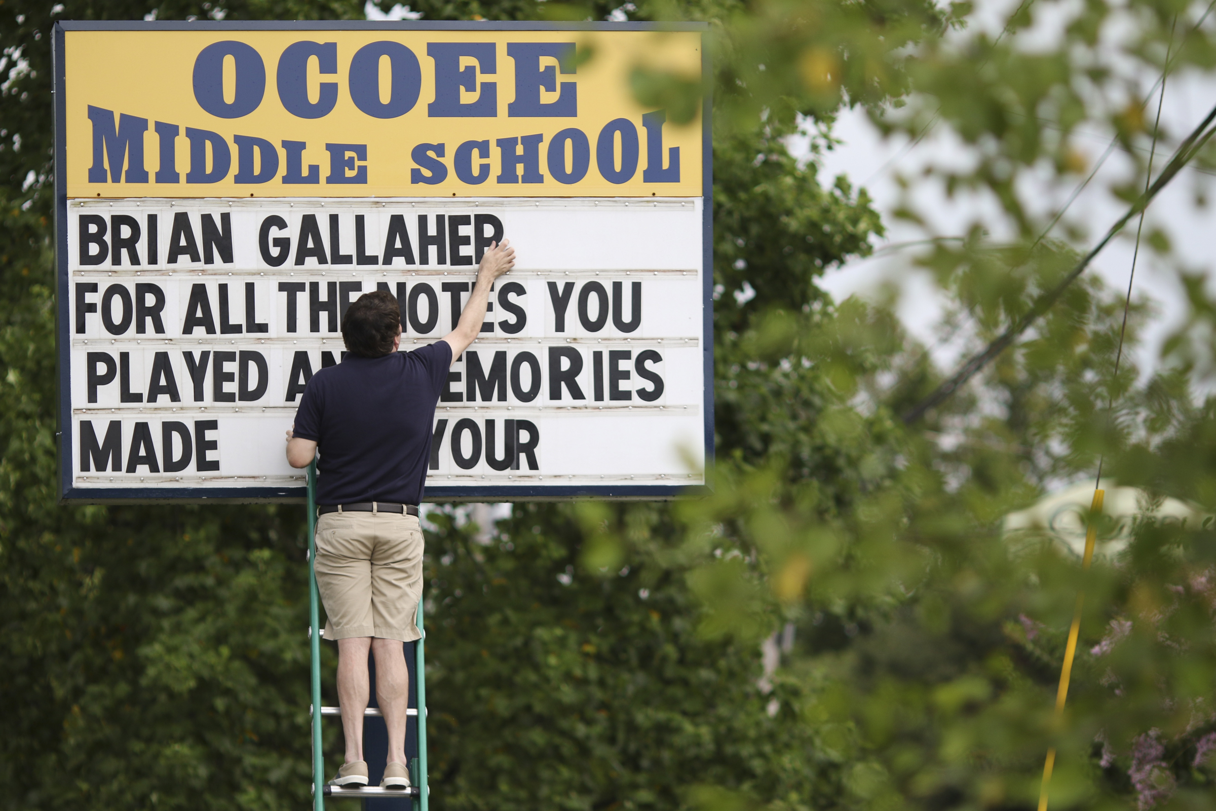 Photo by Dan Henry / The Chattanooga Times Free Press. Kane Ayres, an English teacher at Ocoee Middle School in Cleveland, Tennessee, puts up a memorial message before the start of a candlelight vigil on Friday June 26, 2015 for Ocoee Middle School's band director, Brian Gallaher, who was one of the six people killed in a crash on I-75 late Thursday evening.