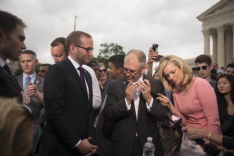 Jim Obergefell, the named plaintiff, center, with HRC President Chad Griffin, left, talks on the phone to President Obama on the steps of the Supreme Court following the Court's decision on Friday, June 26, 2015 in Washington.