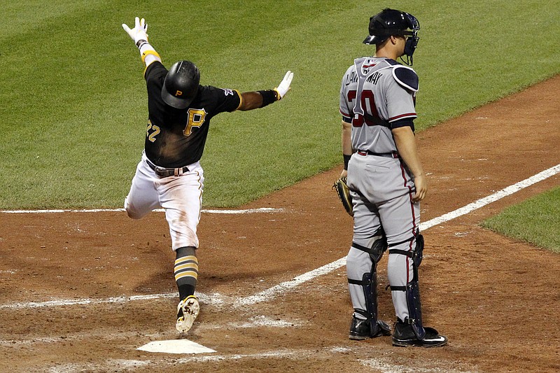 Pittsburgh Pirates' Andrew McCutchen, left, scores behind Atlanta Braves catcher Ryan Lavarnway with the game-winning run on a double by Jordy Mercer in the 10th inning of a baseball game in Pittsburgh, Friday, June 26, 2015. The Pirates won 3-2. 
