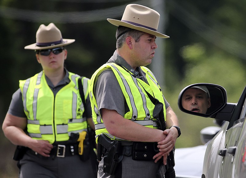 New York State Police troopers talk to a motorist at a roadblock on Saturday, June 27, 2015, in Malone, N.Y. 