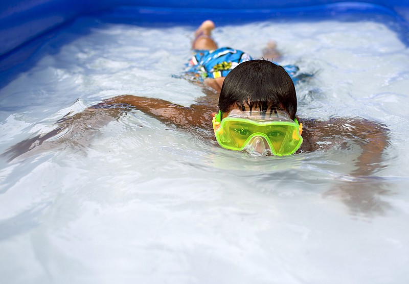 David Kitchens, 8, swims in an inflatable pool in the front yard of his house Tuesday, June 23, 2015, in Bowling Green, Ky. Temperatures are expected to remain in the 90s  through Thursday.  (Austin Anthony/Daily News via AP)  