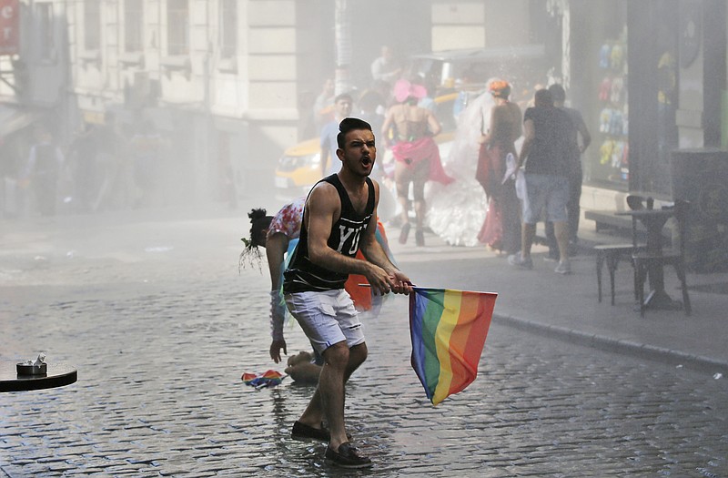 
              A participant in the Gay Pride event in support of  Lesbian, Gay, Bisexual and Transsexual (LGBT) rights reacts as others flee after Turkish police use a water canon to disperse them in Istanbul, Turkey, Sunday, June 28, 2015. Turkish police have used water cannons and tear gas to clear gay pride demonstrators from Istanbul's central square. Between 100 and 200 protestors were chased away from Taksim Square on Sunday after a police vehicle fired several jets of water to disperse the crowd. It wasn't immediately clear why the police intervened to push the peaceful if noisy protest away from the area.  (AP Photo/Emrah Gurel)
            