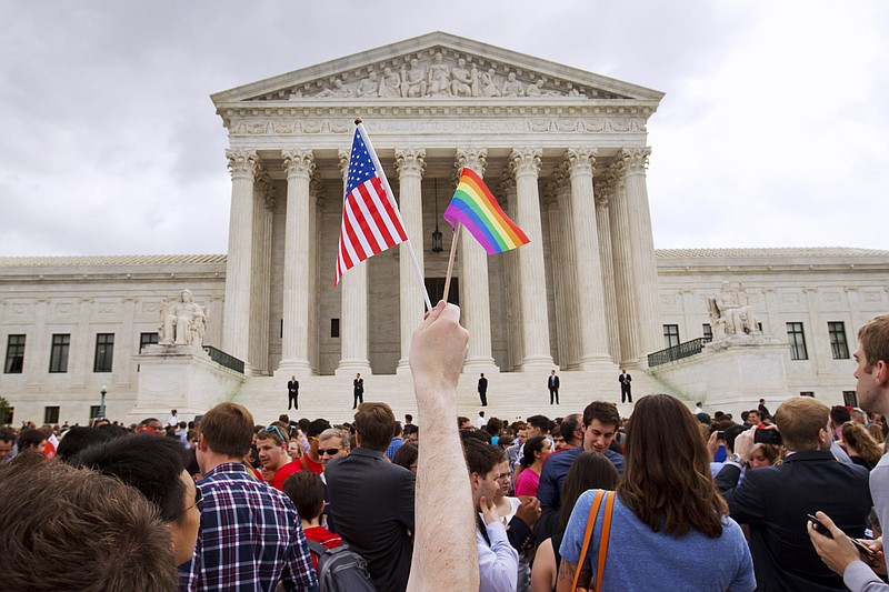 
              FILE - In this Friday June 26, 2015, file photo, a man holds a U.S. and a rainbow flag outside the Supreme Court in Washington after the court legalized gay marriage nationwide. After the decision, religious conservatives are focusing on preserving their right to object. Their concerns are for the thousands of faith-based charities, colleges and hospitals that want to hire, fire, serve and set policy according to their religious beliefs, notably that gay relationships are morally wrong. (AP Photo/Jacquelyn Martin)
            