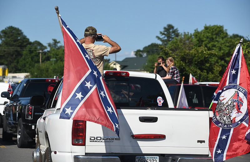 Staff photo by John Rawlston/Chattanooga Times Free Press 
After placing flags on his pickup truck, Allen Baker climbs into the bed to take photos in others participating in a rally for the Confederate flag in the parking lot of the Walnut Square Mall on Sunday, June 28,  2015, in Dalton, Ga. 