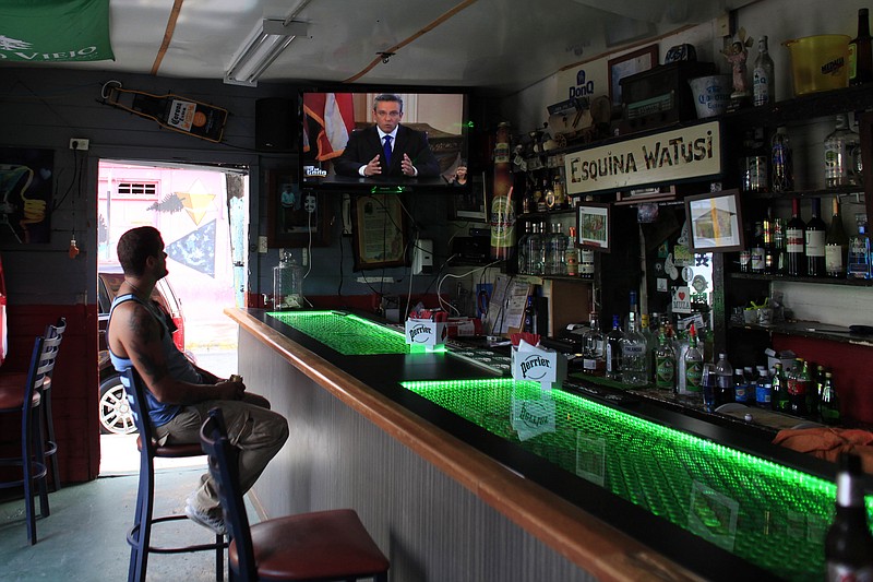 
              A man in a local bar watches Puerto Rico’s governor Alejandro Garcia Padilla on television delivering an address on the state of the island's finances, in San Juan, Puerto Rico, Monday, June 29, 2015. The governor said that he will form a financial team to negotiate with bondholders on delaying debt payments and then restructuring $72 billion in public debt that he says the island can't repay. (AP Photo/Ricardo Arduengo)
            