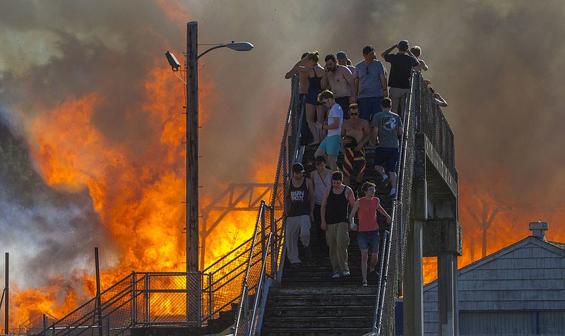
              Onlookers watch the Civic Stadium burn from a bridge in Eugene, Ore., Monday, June 29, 2015. Eugene-Springfield Fire Chief Randy Groves said the stadium's dry, seasoned lumber caused the fire to spread quickly Monday evening. (Andy Nelson/The Register-Guard via AP)
            