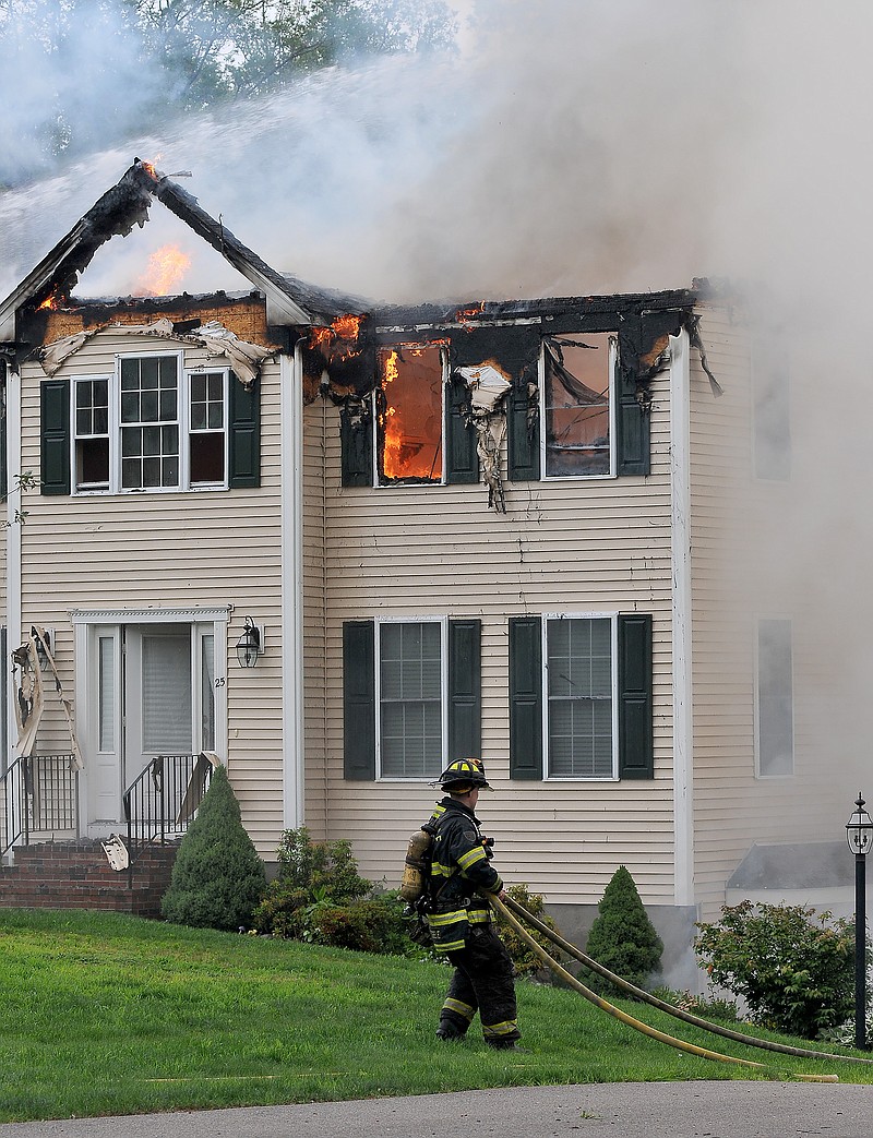 A firefighter moves a hose into position outside a house into which a small plane had crashed in Plainville, Mass., Sunday, June 28, 2015. Jim Peters of the Federal Aviation Administration says the Beechcraft plane crashed into the house at about 5:45 p.m. Sunday. It had taken off from Lancaster Airport in Pennsylvania and was en route to an airport in Norwood, Mass.