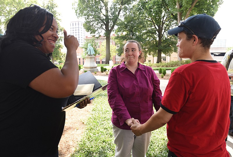 Celebrant Shaun Cox gets ready to perform the wedding ceremony as Phyllis Wood, center, and Rhiannan Pierce hold hands Friday at the Hamilton County Courthouse.