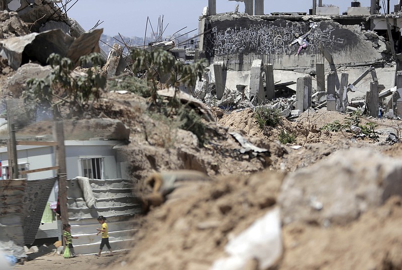 
              In this June 17, 2015 photo, Palestinian girls are seen reflected in a mirror as they walk next to rubble in the area where they live with family after losing their house in Gaza City. A year after the most destructive war in Gaza yet, Hamas remains in control, despite signs of mounting frustration and a poll indicating half the residents would emigrate if borders were open. (AP Photo/Khalil Hamra)
            