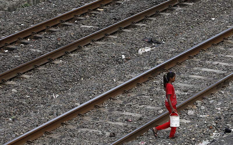 
              An Indian girl holds a can filled with water and walks past railway tracks to defecate in the open in Mumbai, India, Tuesday, June 30, 2015. Toilets are taken for granted in the industrialized West, but still are a luxury for a third of the world's people who have no access to them, according to a report by the World Health Organization and UNICEF released Tuesday. India is by far the worst culprit, with more than 640 million people defecating in the open, and not necessarily due to a lack of facilities. (AP Photo/Rajanish Kakade)
            
