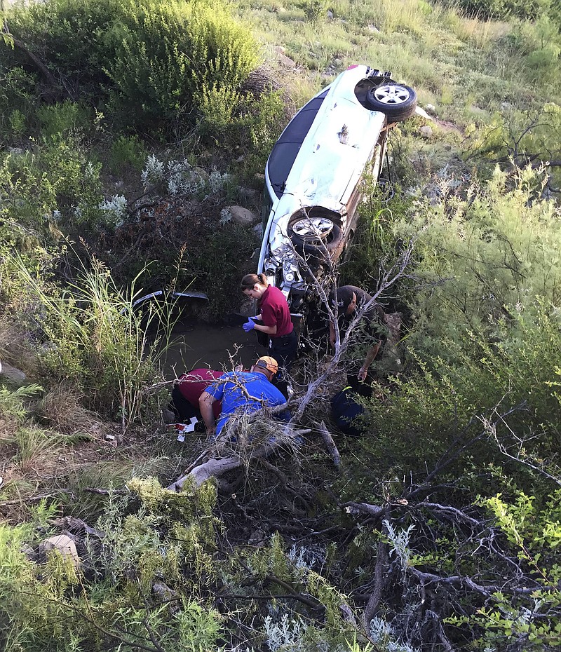 
              In this photo provided by Brandon Cogburn, workers stand near the wrecked car of Wanda Mobley where she was found Sunday, June 28, 2015, near Seymour, Texas. The 75-year-old woman says she couldn't walk after crashing her car into a ravine in North Texas, but survived for two days after pulling herself through a broken windshield and soaking her T-shirt in a nearby pond to get water. (Brandon Cogburn via AP)
            