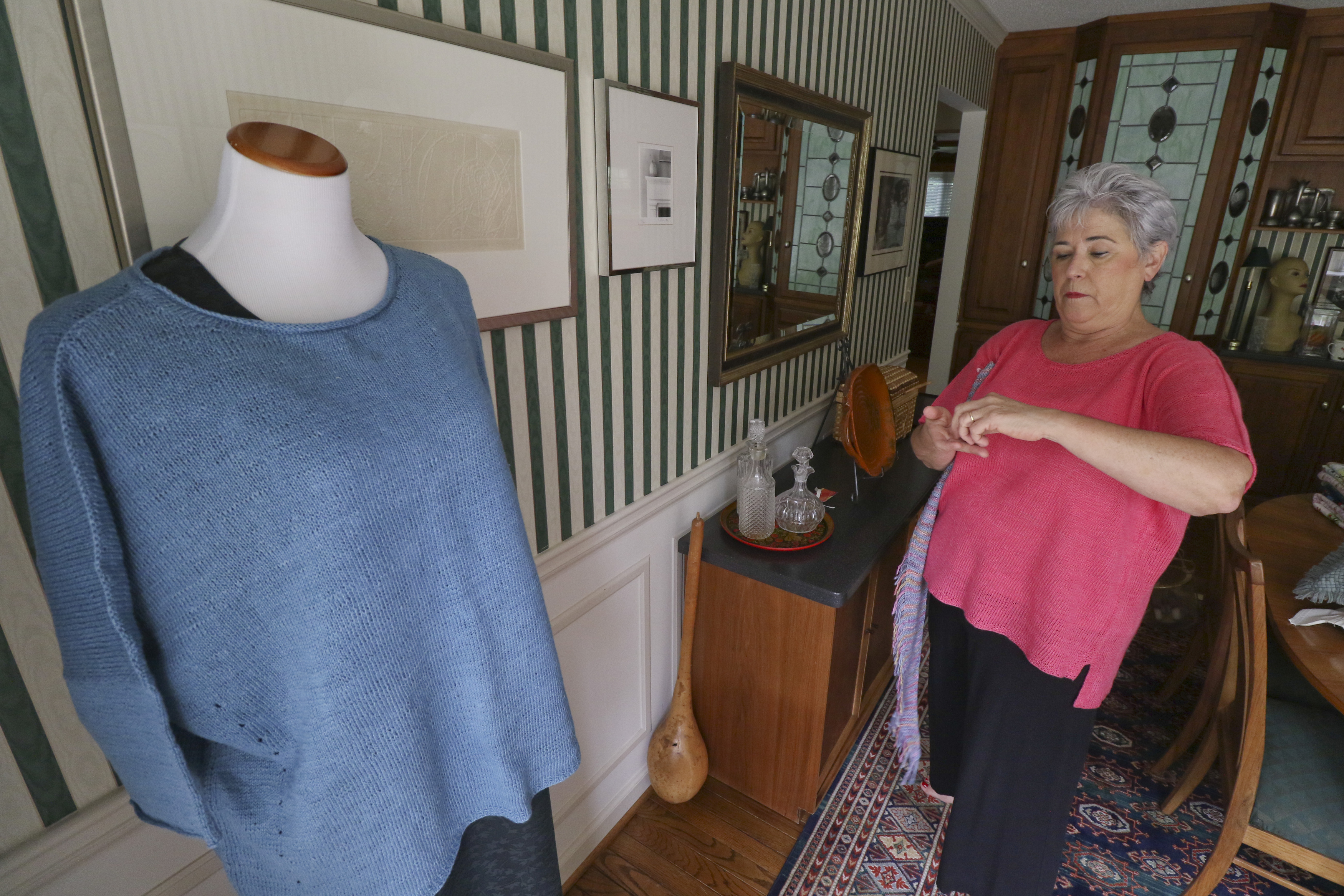 Staff Photo by Dan Henry. Nancy Hall dresses a figure form with items that she has knitted before taking photos of them to post to her MyParadeDesigns storefront on Etsy.